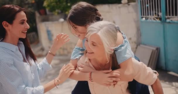 Mormor, barnbarn och vuxen dotter har kul med piggyback ride — Stockvideo