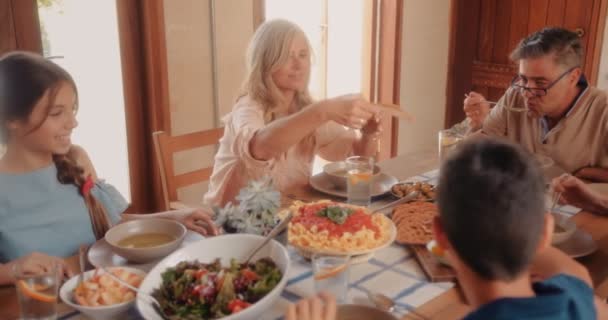 Glad familj med morföräldrar som äter lunch i rustikt stughus — Stockvideo