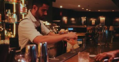 Barmen lüks retro bar tezgahında kokteyl yapıp servis ediyor.