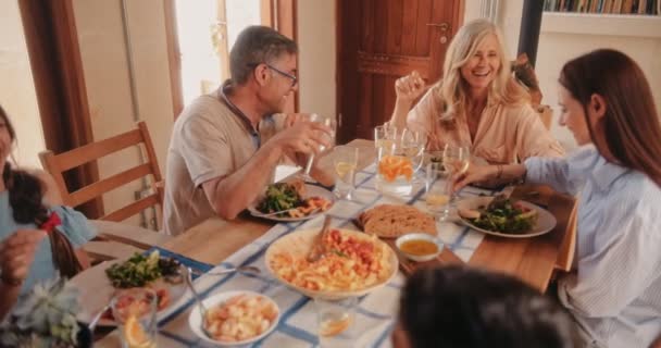 Glad flergenerationsfamilj som äter Medelhavslunch och skålar med vin — Stockvideo