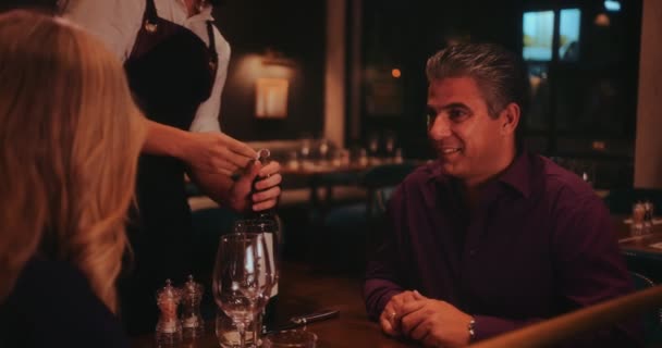Starší pár na večeři s mužem ochutnávka vína před podáváním — Stock video