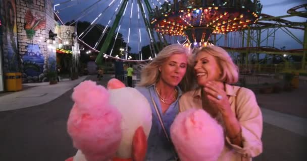 Mogna kvinnor äter sockervadd och har kul på tivoli — Stockvideo