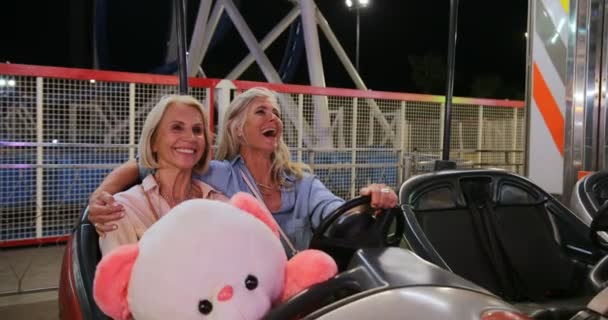 Mulheres maduras felizes no parque de diversões sentado no carro pára-choques — Vídeo de Stock