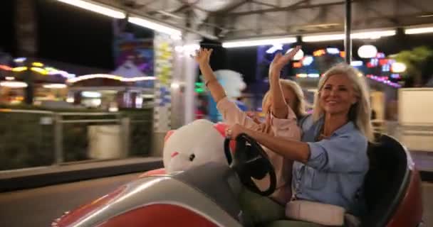 Mulheres maduras felizes dirigindo carro pára-choques no parque de diversões — Vídeo de Stock