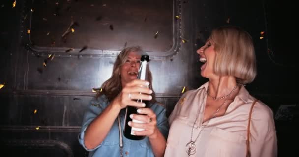 Boldog érett nők ünnepelnek pezsgővel és konfettivel éjszaka — Stock videók