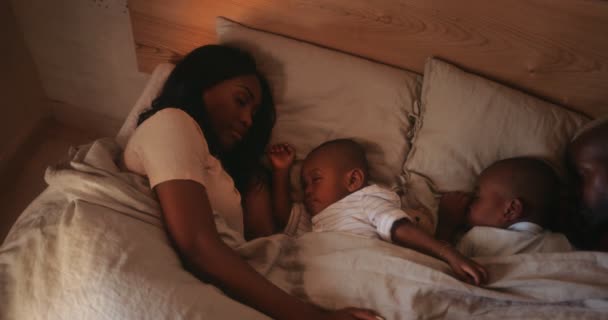 Young loving couple sleeping in bed with little sons — Stock Video