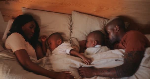 Молодая любящая пара с маленькими детьми спят вместе в постели — стоковое видео