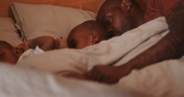 Bekar baba ve oğullu bir aile yatakta birlikte yatıyor.