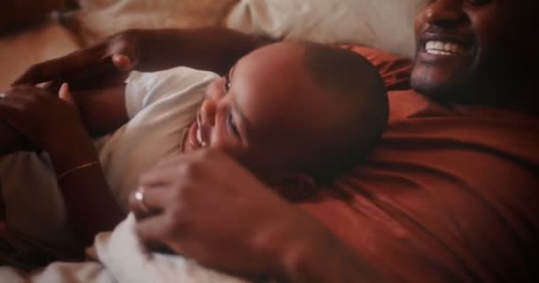 Щасливий люблячий батько грає з маленьким сином у ліжку — стокове відео
