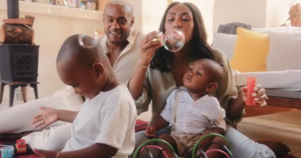 Pais felizes brincando com crianças e soprando bolhas em casa — Vídeo de Stock