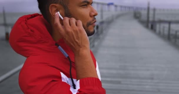 Afro-americký muž klepání sluchátka před spuštěním u řeky — Stock video