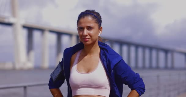 Mujer segura de pie con las manos en las caderas por el puente del río — Vídeo de stock