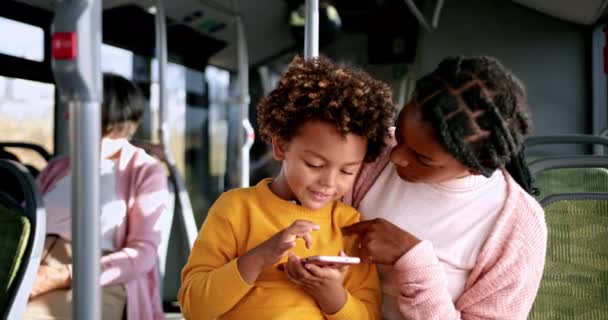 Menino afro-americano brincando com telefone no colo da mãe dentro do ônibus — Vídeo de Stock