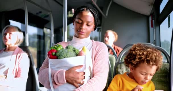 Afro-americano ragazzo in possesso di smartphone e madre con generi alimentari su autobus — Video Stock