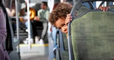 Afro-Amerikalı küçük çocuk halk otobüsünde dikiz oyunu oynuyor.