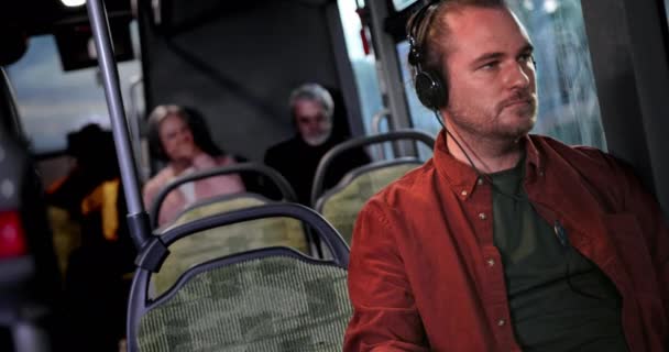 Homem sentado dentro do ônibus público ouvindo música em fones de ouvido — Vídeo de Stock