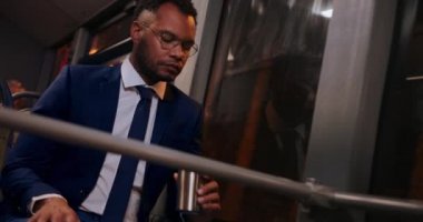 Afro-Amerikalı iş adamı otobüste kahve içiyor.