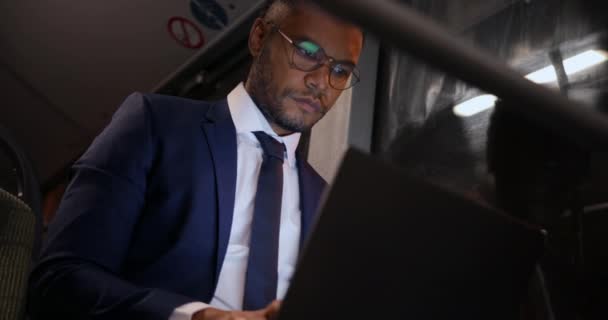 Homem de negócios afro-americano trabalhando em laptop em ônibus público — Vídeo de Stock