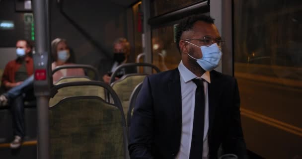Afroamerikansk affärsman klädd i covid ansiktsmask på bussen — Stockvideo