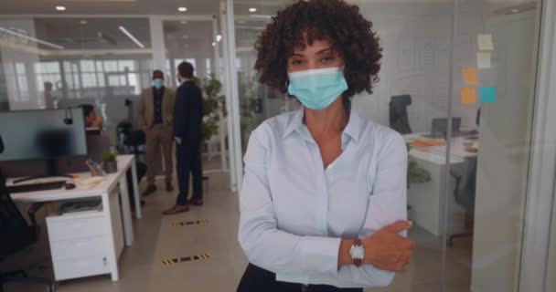 Деловая женщина со скрещенными руками и ковидовой маской в офисе — стоковое видео