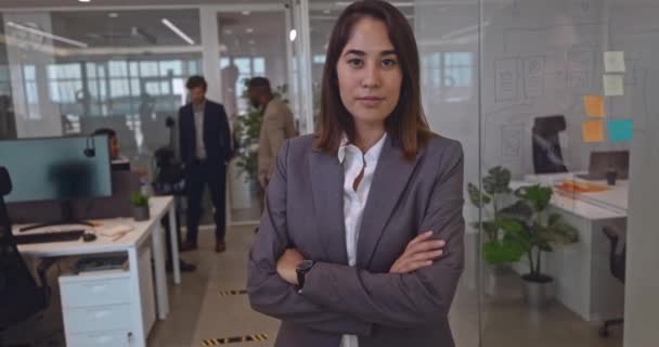 Молодая азиатская предпринимательница, опирающаяся на стеклянную стену в современном офисе — стоковое видео