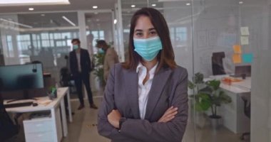 Modern ofiste maske takan Asyalı genç bir iş kadını.