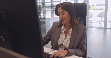 Çağrı merkezinde kulaklık takmış Asyalı genç bir kadın çalışıyor.