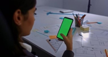 İş kadını ofisteki akıllı telefon yeşil ekranında kayıyor.