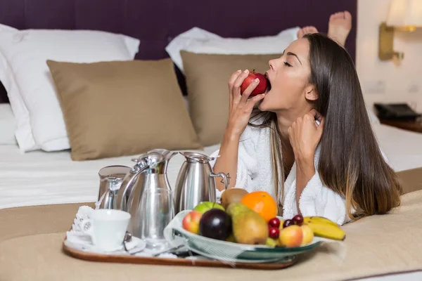 Hermosa Morena Tumbada Cama Con Comida Servida Bandeja Mordiendo Manzana —  Fotos de Stock