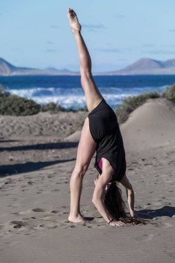 Yalınayak şort yükseltti kıyı güneş ışığında eğitim yoga sırasında bacak ile ayakta kadında yan görünüm