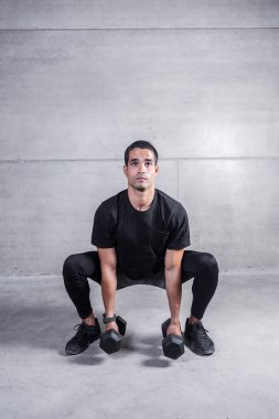 Odaklı bodur dumbbells holding ve gri beton zemin üzerinde egzersiz yapıyor atletik adam 