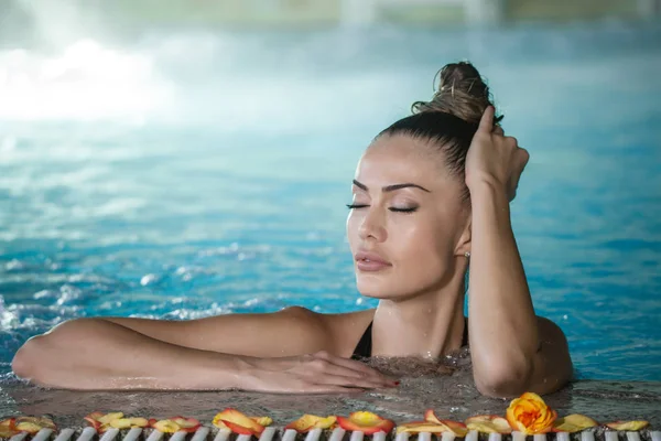 Чувственная женщина касается влажных волос в бассейне — стоковое фото