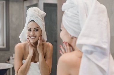 Duştan sonra yüze dokunan neşeli kadın