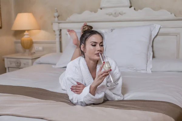 Sensuele vrouw ruikende Champagne op bed — Stockfoto