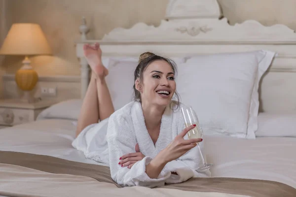 Веселая женщина наслаждается шампанским в отеле — стоковое фото