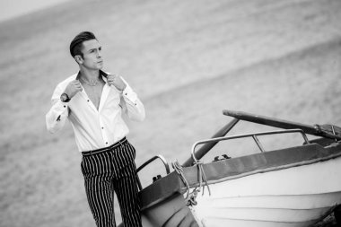 Alluring trendy male standing by boat clipart