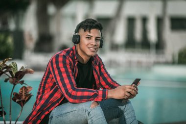 Neşeli İspanyol erkek havuz kenarında müzik dinliyor