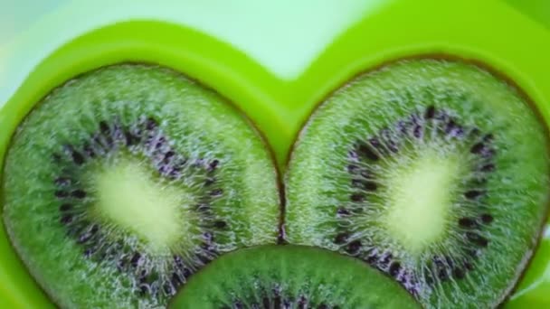 Skivor kiwi roterar på en grön bakgrund. Ovanifrån. Närbild. — Stockvideo