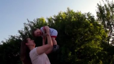 Annem mutlu oğlunu gökyüzüne fırlattı. Annenin kollarındaki bebek. Mutlu aile kavramı.