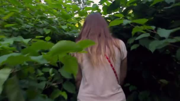 Moeder met een baby in een wandelwagen loopt in het park in dichte vegetatie — Stockvideo