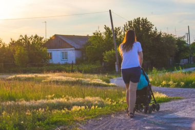 Bebek arabalı bir kız, kırsalın arka planında.