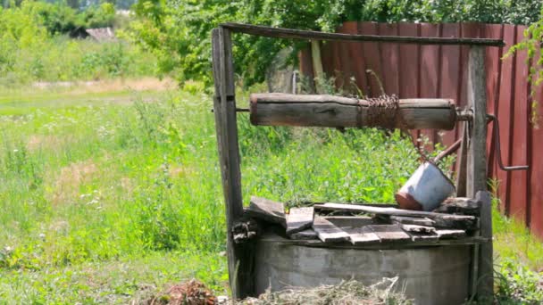 En manuell brunn framför ett lantligt hus som ger grundvatten som dricksvatten för byborna. — Stockvideo
