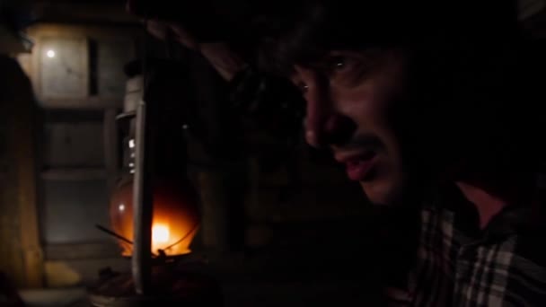 Un tânăr într-o casă veche luminează o cale cu o lampă de kerosen — Videoclip de stoc