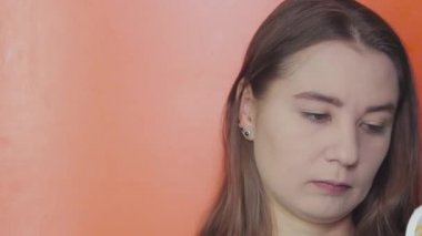 Yakın plan. Turuncu arka planda genç bir kız yüzüne temel atar. Makyaj konsepti. Boşluğu kopyala