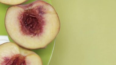 Şeftali meyvesinin yarısı yeşil-sarı arka planda döner. Boşluğu kopyala