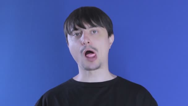 Portrét muže, který těžce žvýká žvýkačku na modrém pozadí — Stock video