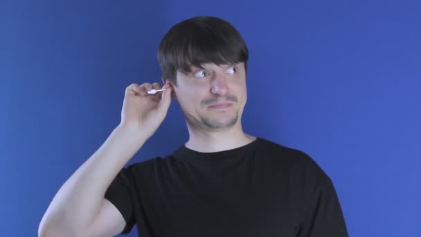Мужчина чистит уши ватным тампоном и вытаскивает ушную серу — стоковое видео