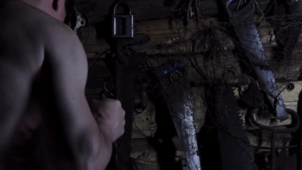 Louco e assustador homem caucasiano a serrar com uma serra numa velha casa abandonada. espaço de cópia — Vídeo de Stock