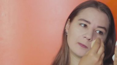 Turuncu arka planda genç bir kız yüzüne temel atar.