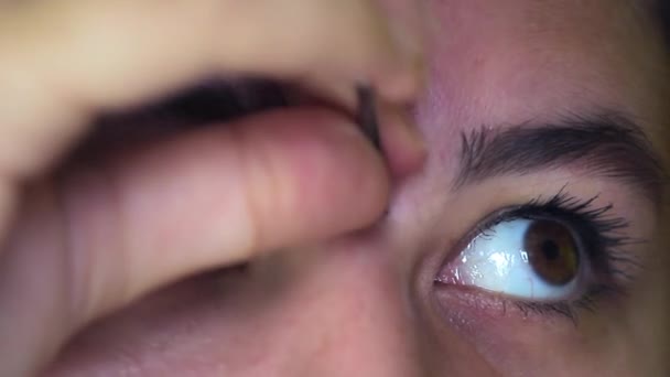 Menina caucasiana com olhos castanhos arrancando sobrancelhas com pinças. Close-up — Vídeo de Stock